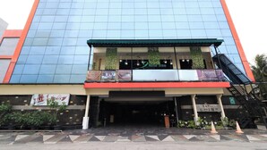 Un hotel moderno con fachada de vidrio, toldo verde y un cartel que dice 'Hotel Coins'.