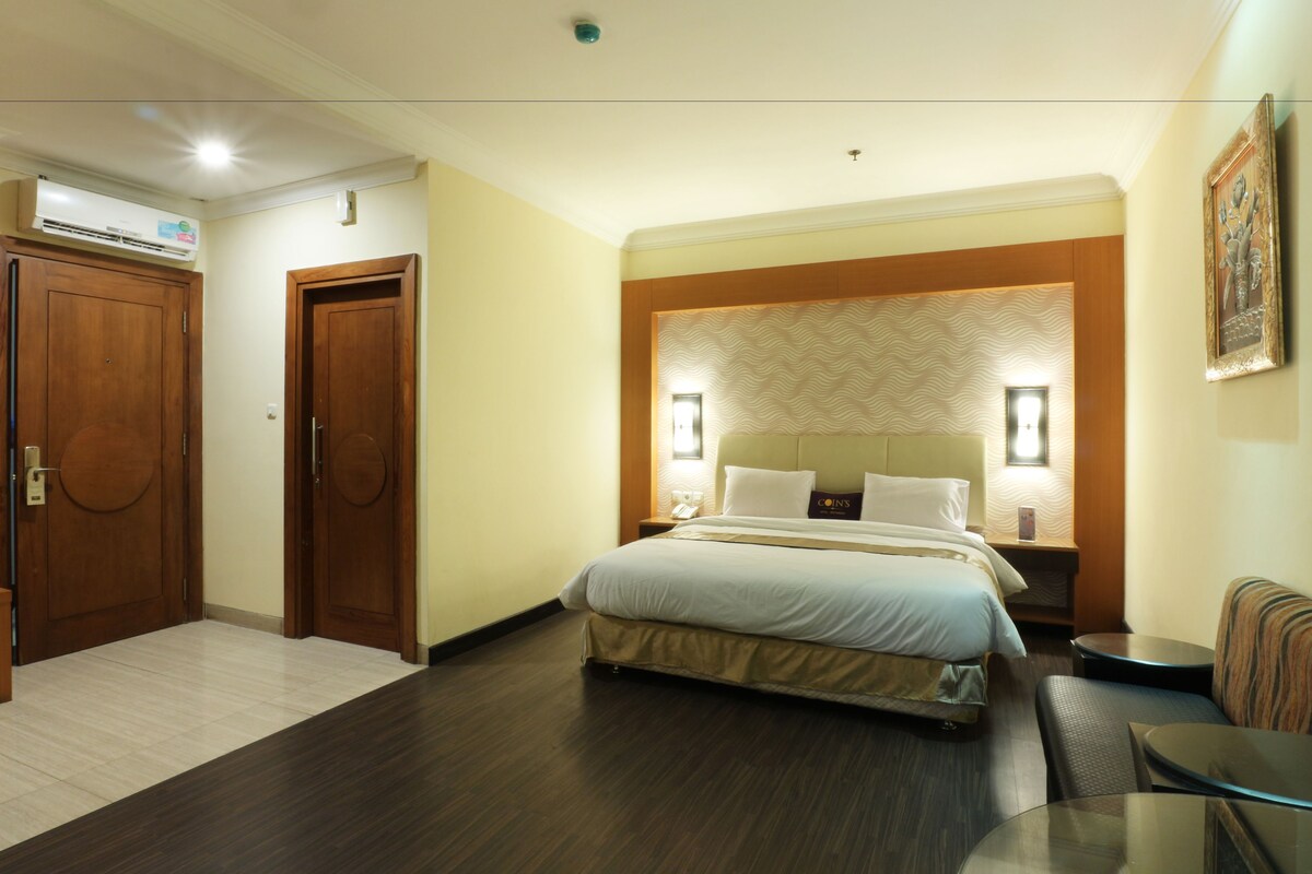 Una habitación de hotel con cama, zona de estar, una mesa y una puerta.