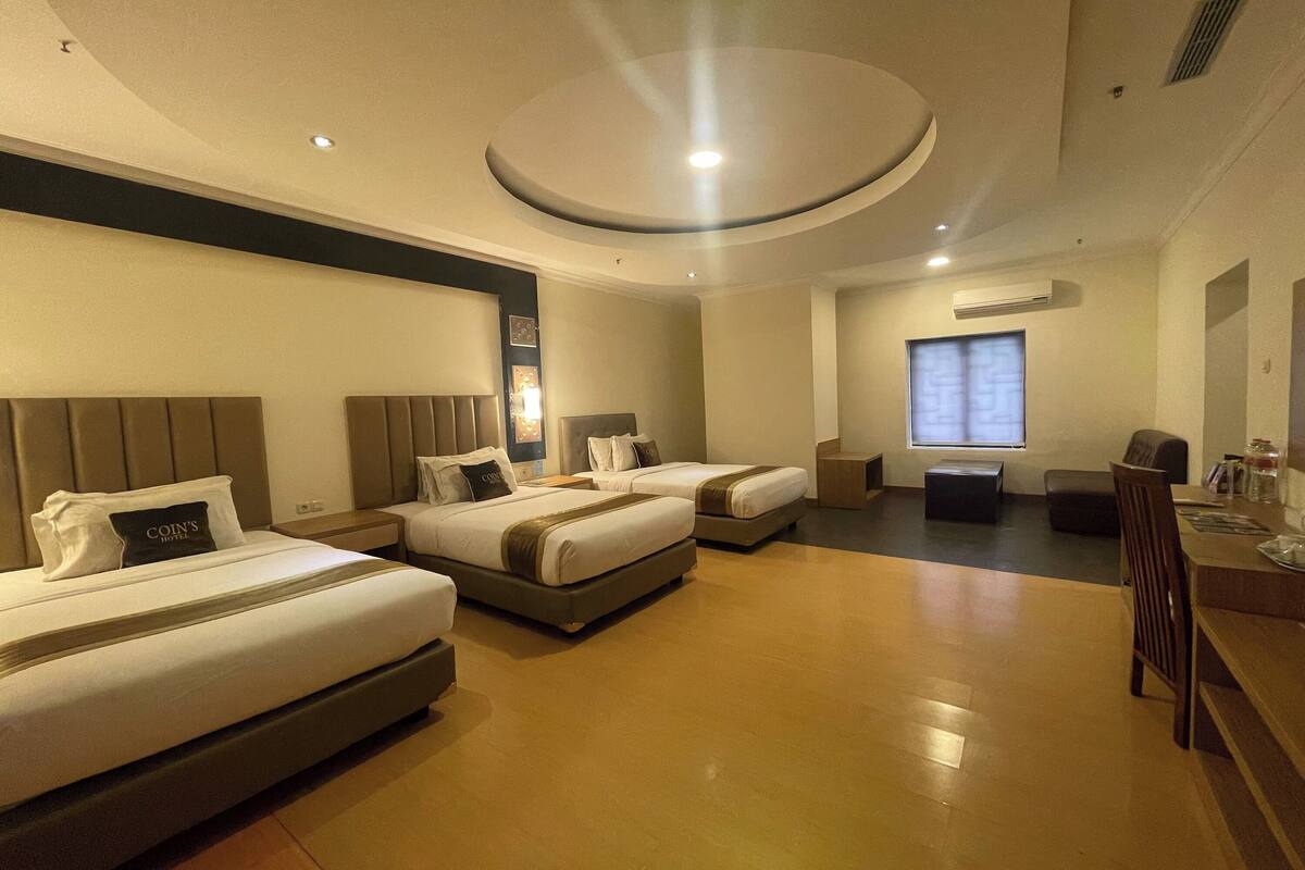 A hotel room with two beds, a desk, and a chair.