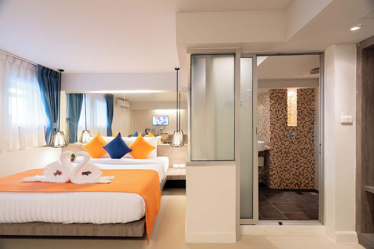 A hotel room with two beds, a bathroom, and a TV.