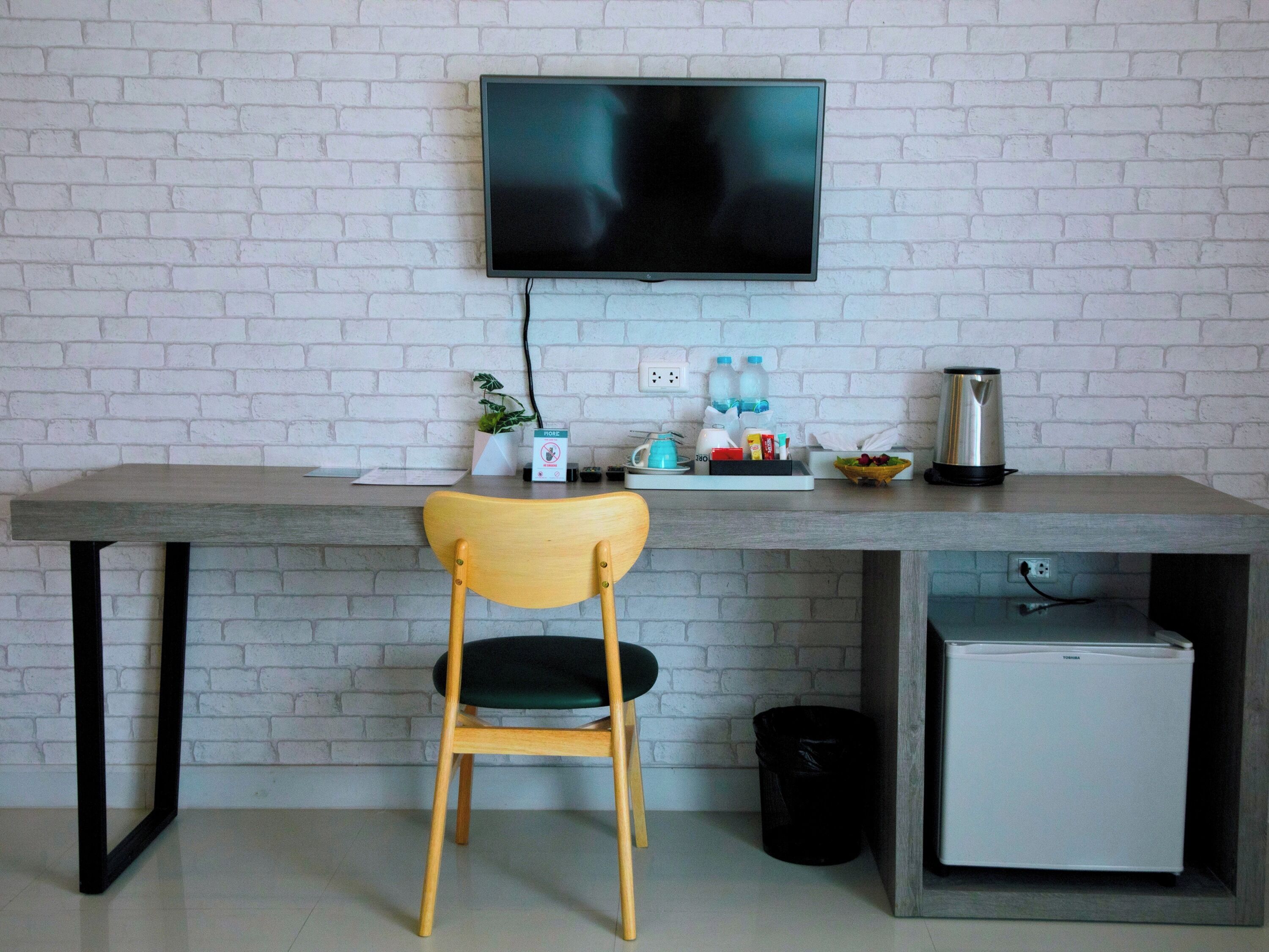 A modern workspace with a desk, chair, TV, and a small refrigerator.