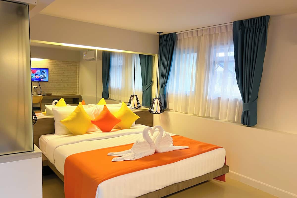 A hotel room with a bed, a TV, a desk, and a mirror.