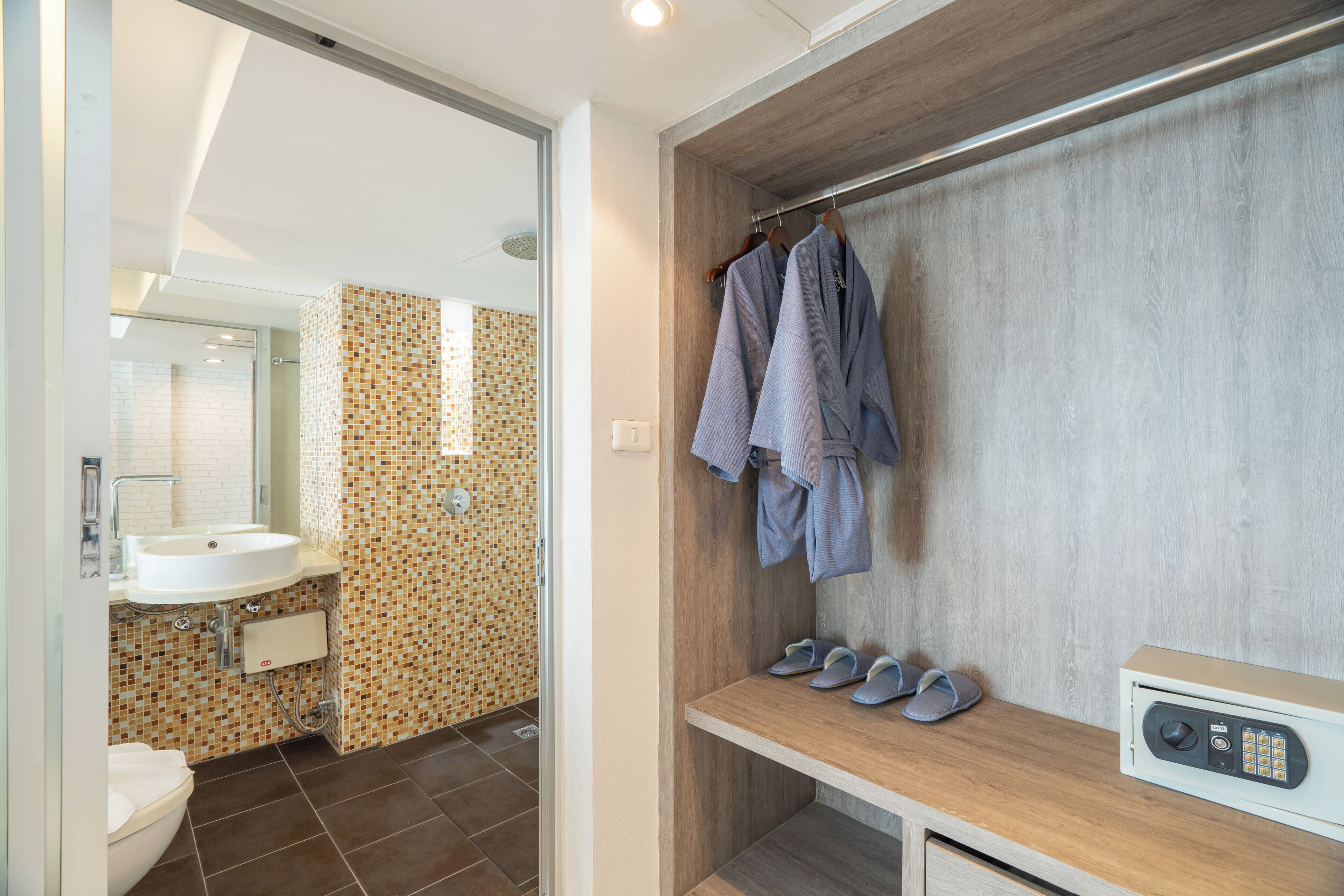 A bathroom with a sink, mirror, and tiled walls. There is a bench with shoes and a radio.