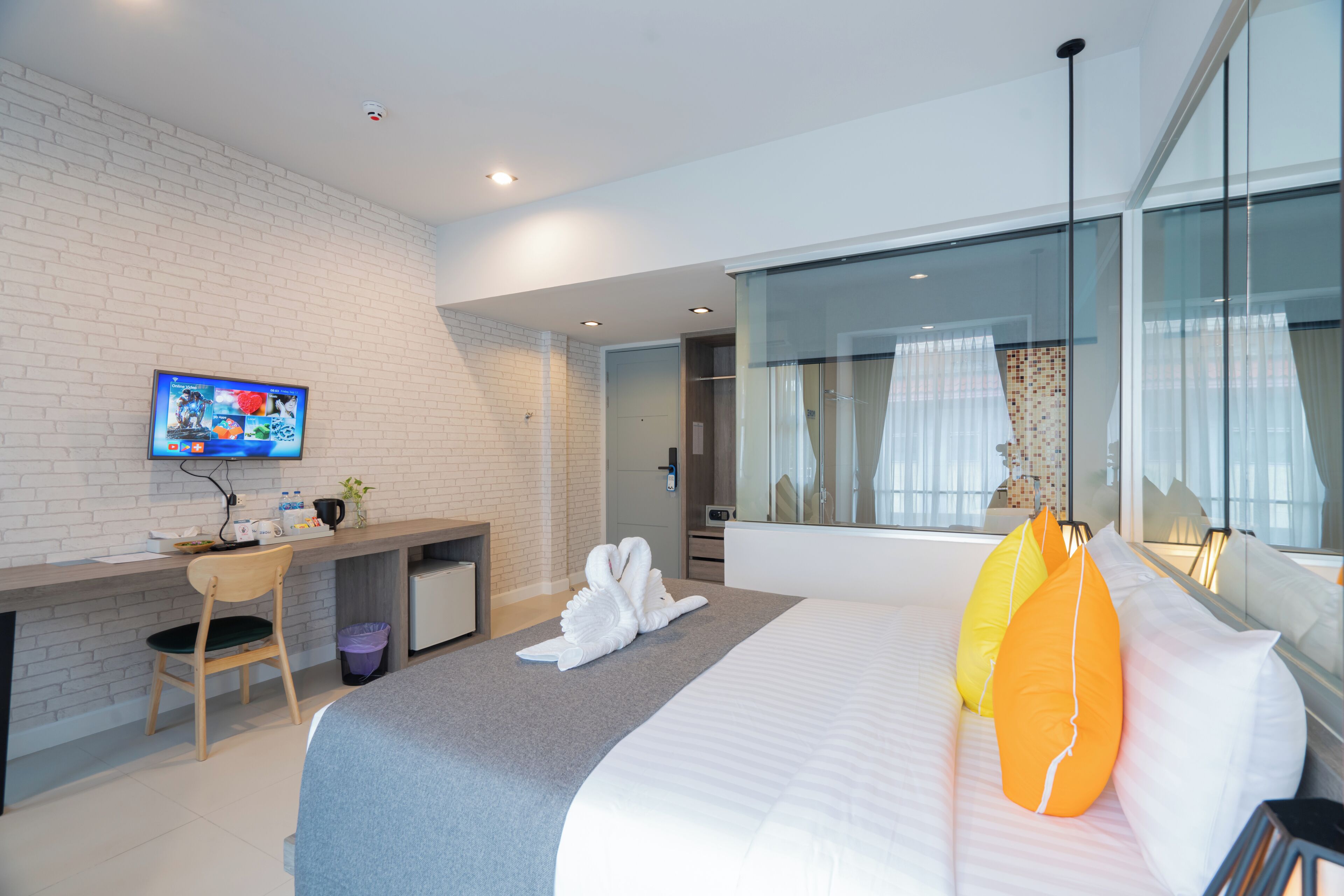 Ein Hotelzimmer mit Bett, Schreibtisch, Fernseher und einem großen Fenster.
