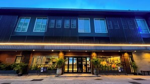 Ein modernes Hotel mit dunkler Fassade, großen Fenstern und einem gut beleuchteten Eingang.