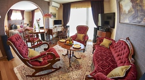 A spacious living room with a large TV, comfortable seating, a dining area, and a view of the outdoors. - Zenith Boutique Lodge & Spa (Wellington)