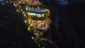 A multi-story building with a rooftop terrace, surrounded by trees and illuminated by ambient lighting. - Zenith Boutique Lodge & Spa (Wellington)