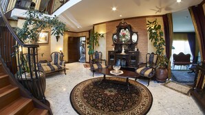 A spacious living area with a grand staircase, a fireplace, and multiple seating arrangements. - Zenith Boutique Lodge & Spa (Wellington)