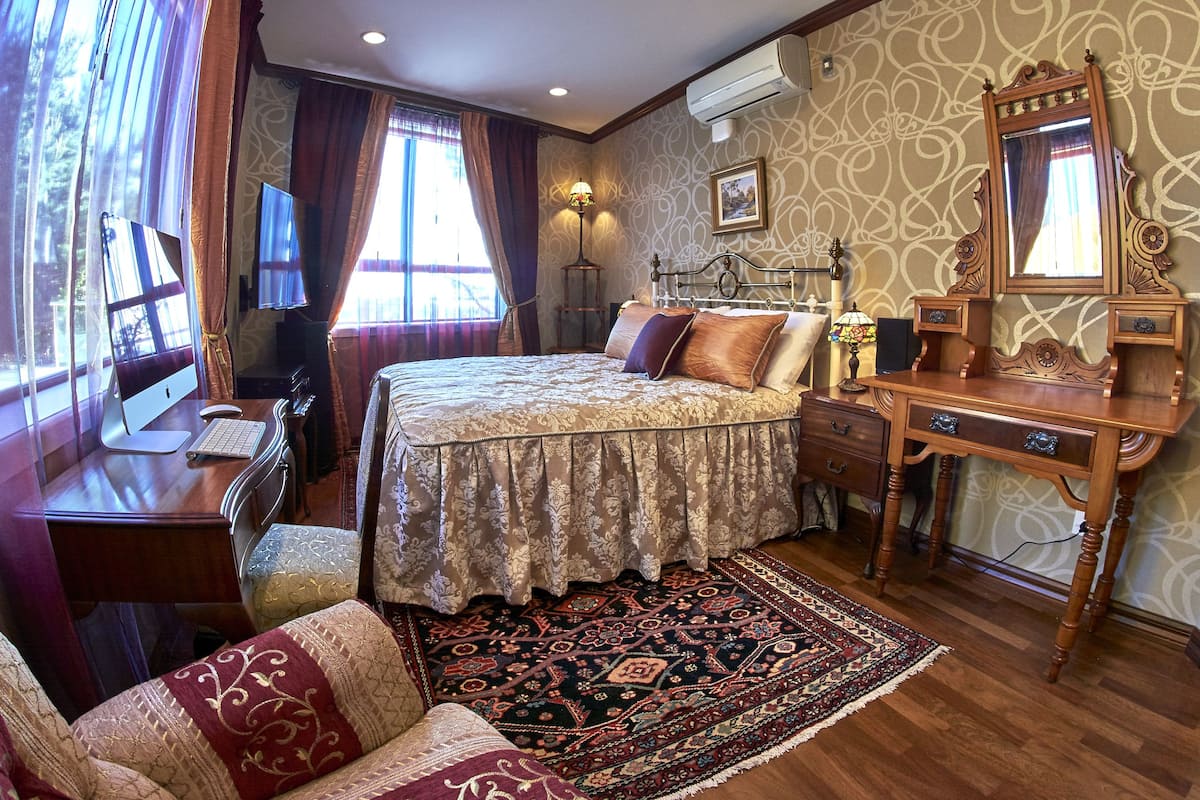 Un dormitorio con cama, escritorio, silla y un espejo grande.