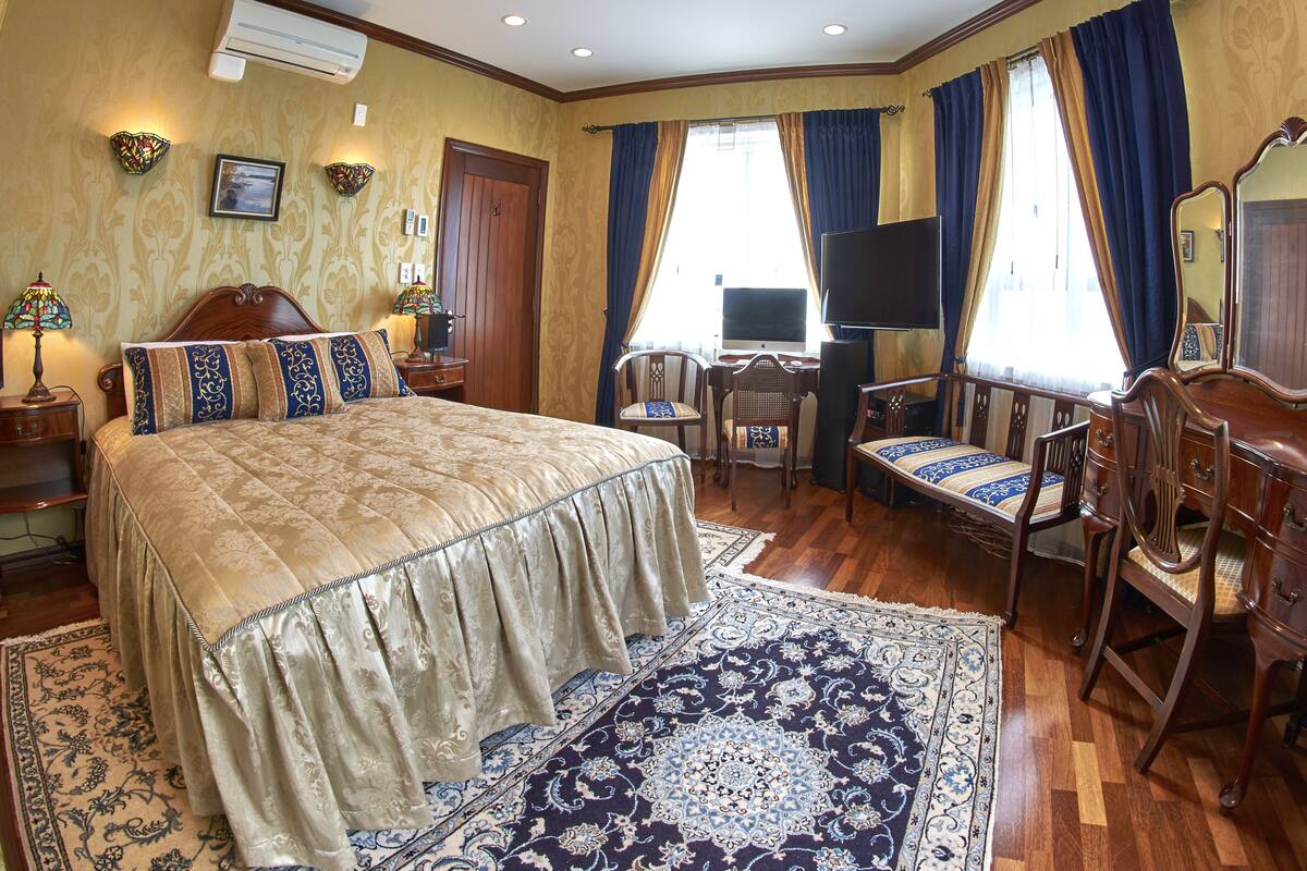 Un dormitorio elegante con una cama grande, un escritorio, una silla, un aparador y un televisor.