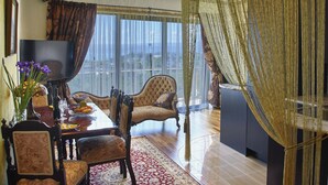 A spacious living room with a large window, a television, a dining table, and comfortable seating. - Zenith Boutique Lodge & Spa (Wellington)