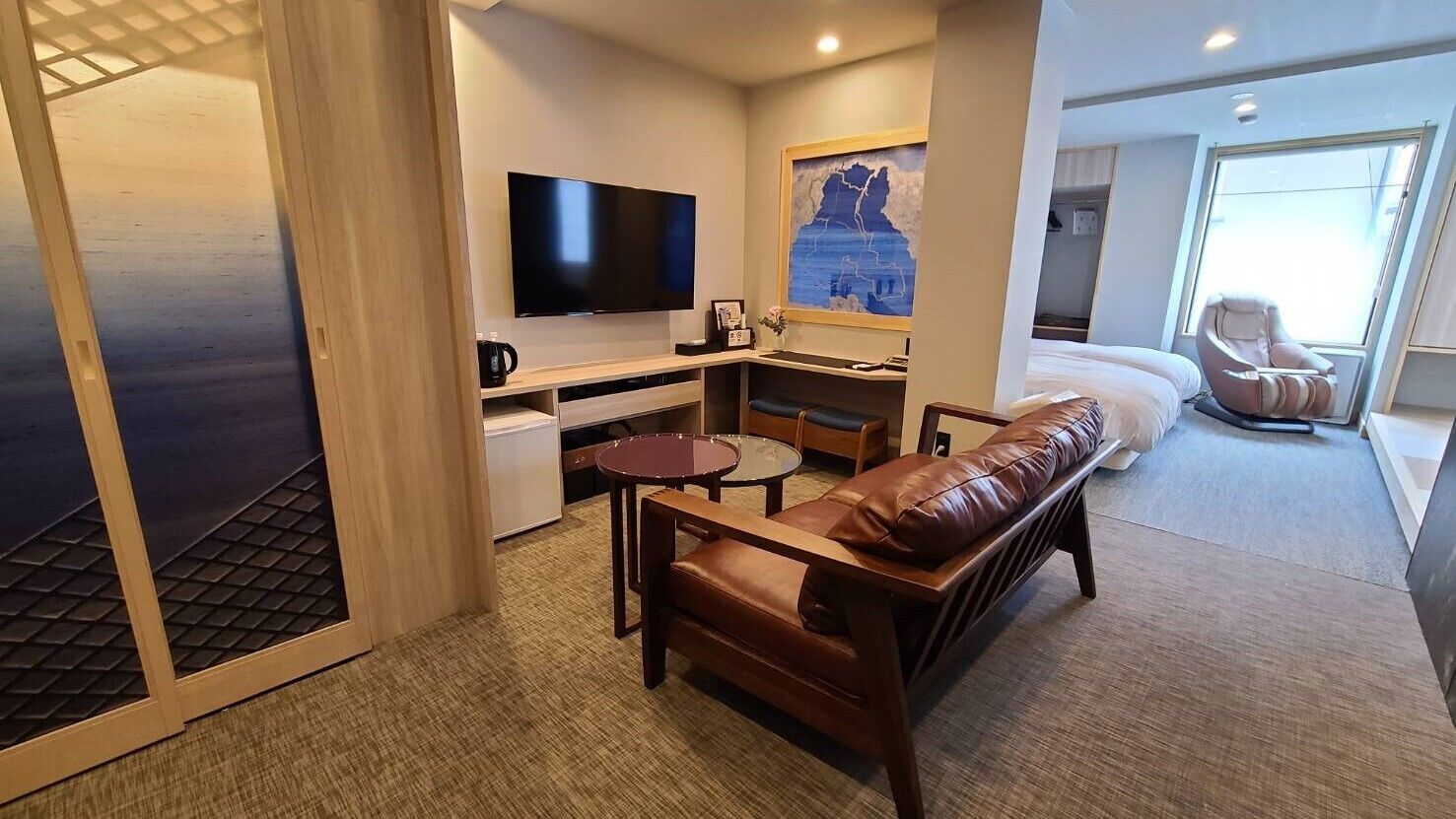 Une chambre d’hôtel compacte équipée d’une télévision, d’une petite kitchenette, d’un canapé et d’un lit.