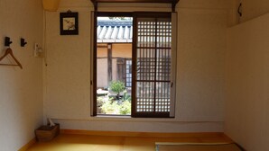 A traditional Japanese room with tatami flooring, a sliding door with a view of a garden, and a hanging lantern. - Gyeamgotaek (Seosan)