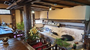 A rustic interior with a wooden dining table, chairs, a sewing machine, and a shelf with framed photos. - Gyeamgotaek (Seosan)