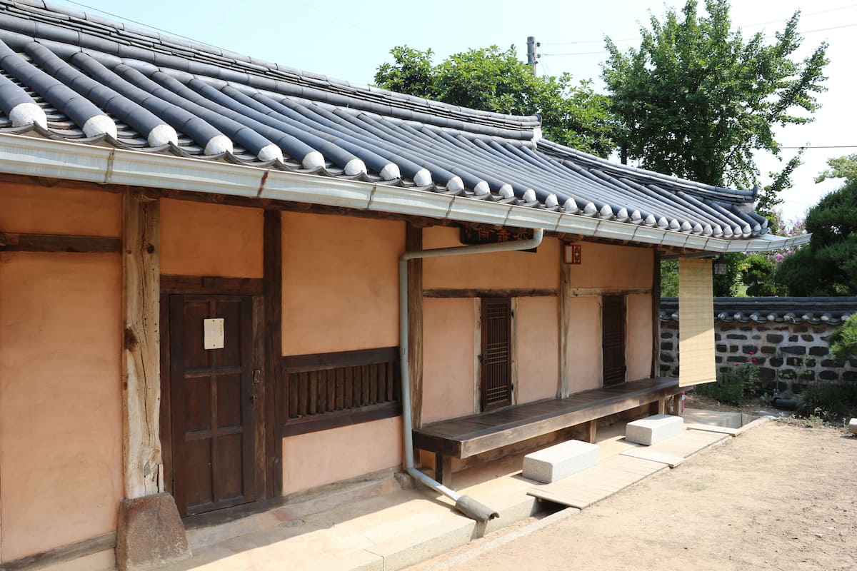 A traditional building with a tiled roof, wooden door, and a small porch area.