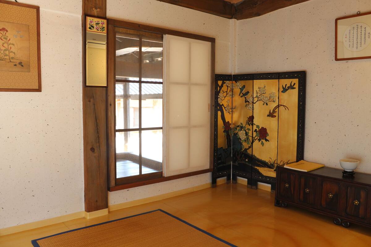 A traditional Japanese room with tatami flooring, a sliding shoji screen, and a wooden cabinet with a bowl.