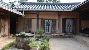 A traditional courtyard with stone steps, potted plants, and a tiled roof. - Gyeamgotaek (Seosan)