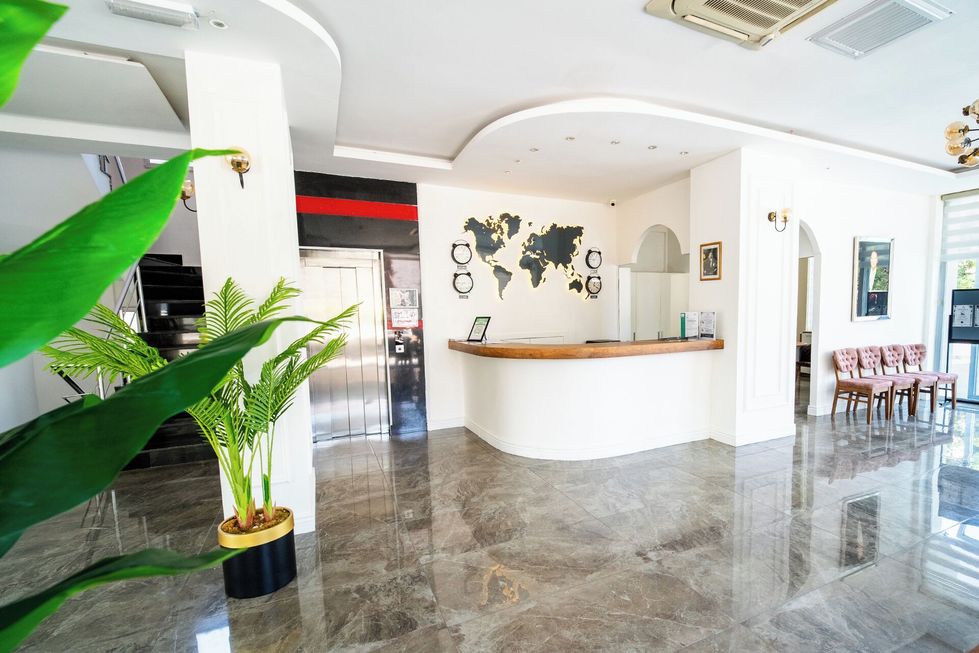 A hotel lobby with a reception desk, a world map, clocks, and a staircase.