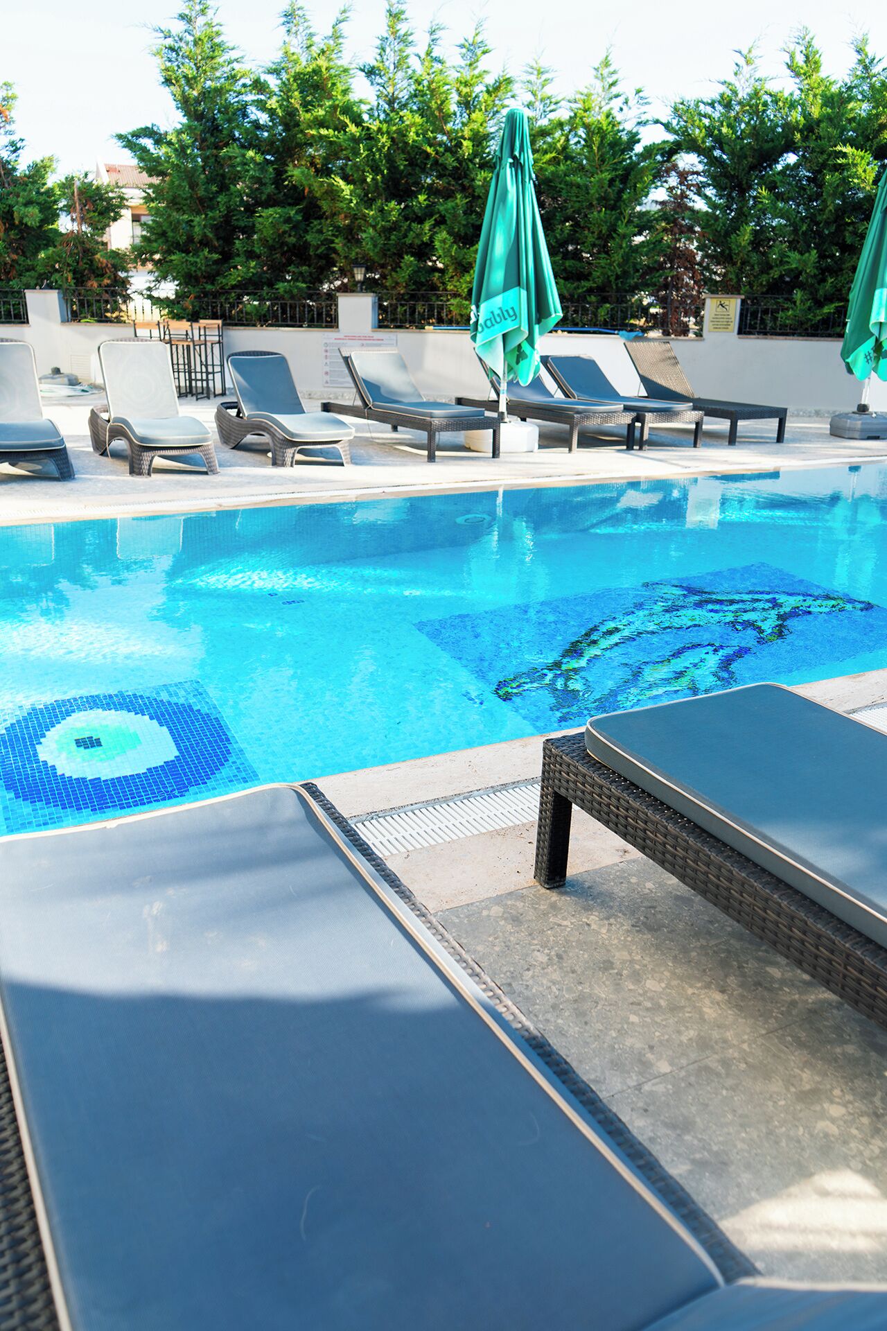 A swimming pool with lounge chairs and a covered umbrella.