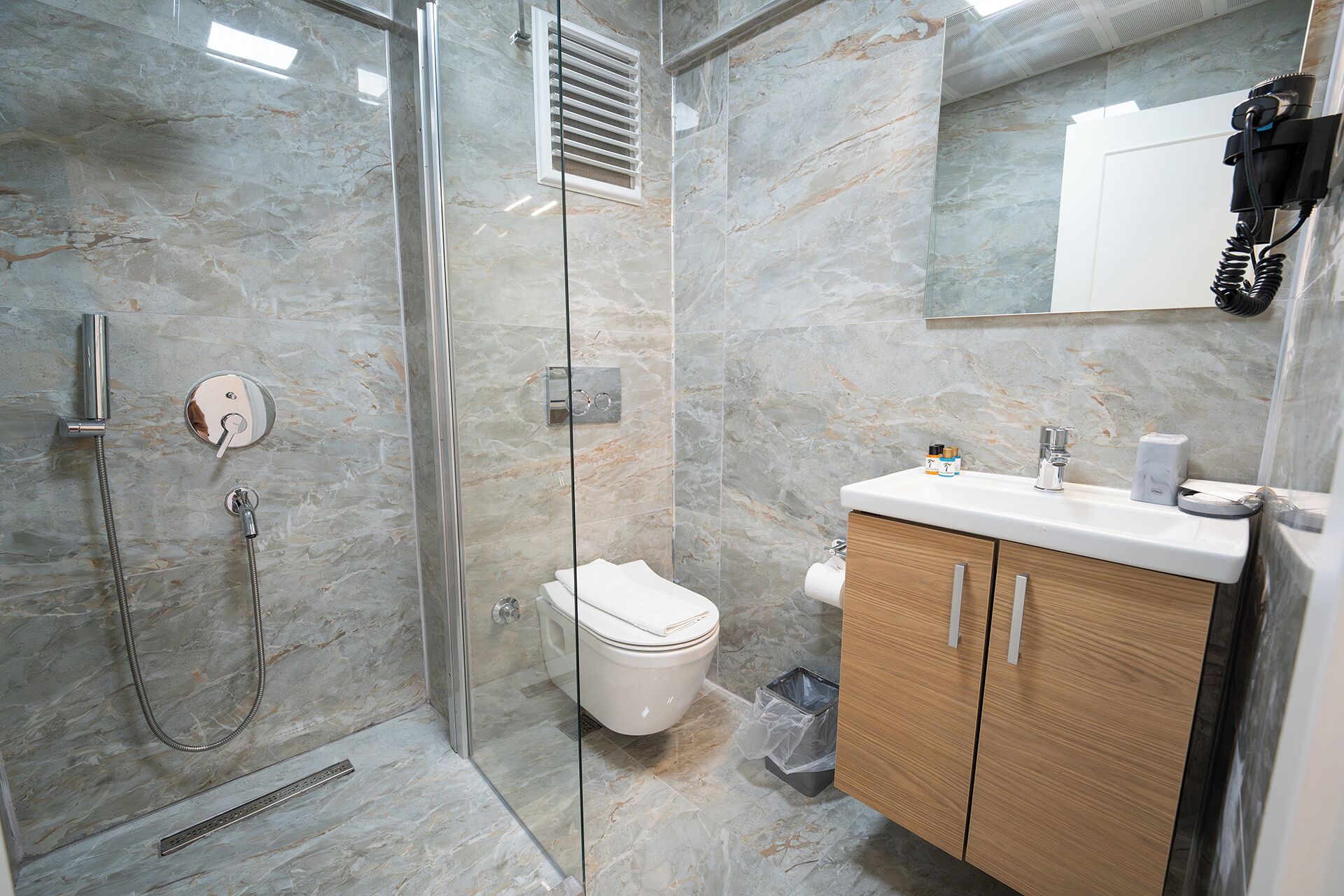 Une salle de bain moderne avec une douche à parois de verre, des toilettes et un meuble-lavabo en bois avec un évier.