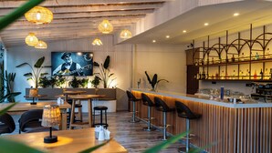 A bar area with wooden bar stools, a counter with a variety of bottles, and hanging wicker lamps. - Aurasia SeaSide Hotel (Marmaris)
