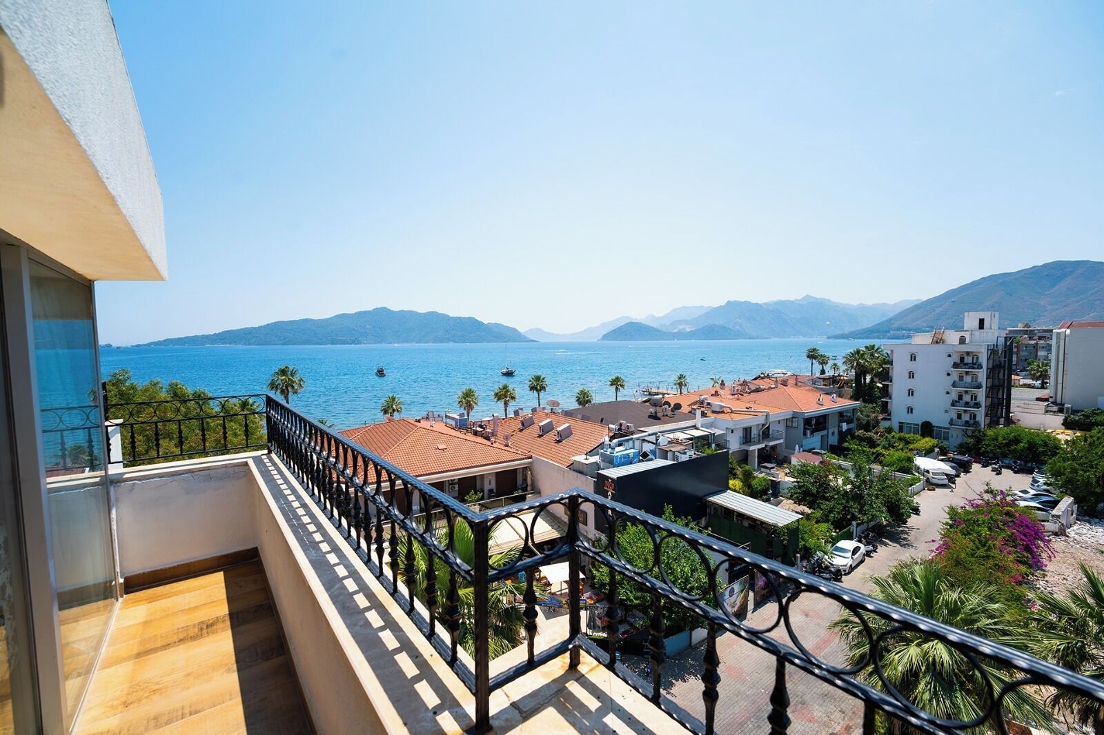Un balcon donnant sur une ville côtière, avec vue sur les bâtiments et une mer bleue et limpide.