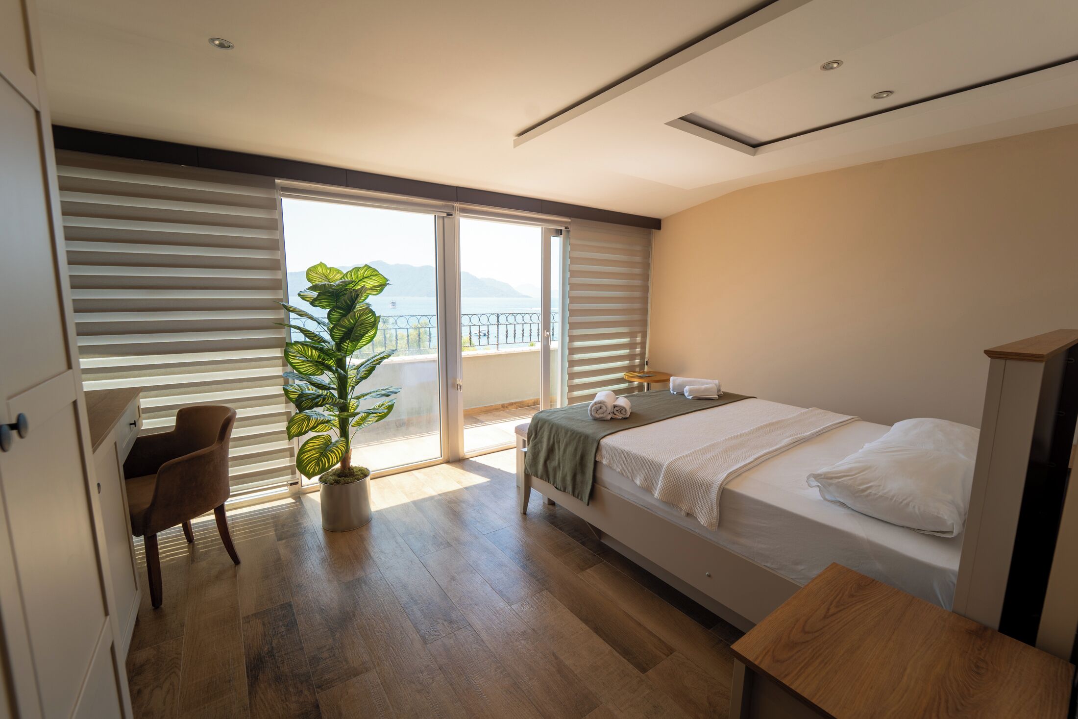 Une chambre à coucher avec un lit, un bureau, une chaise et une grande plante.