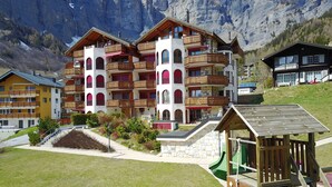 Un hôtel à plusieurs étages doté de balcons, d’un espace de jeux et offrant une vue sur les montagnes.
