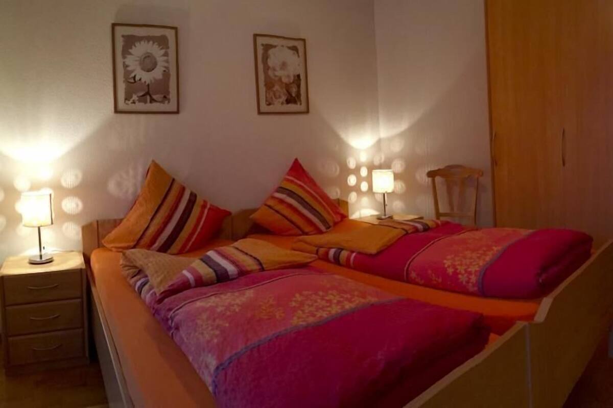 Ein Schlafzimmer mit einem Bett, Nachttischen, Lampen und zwei Bildern an der Wand.