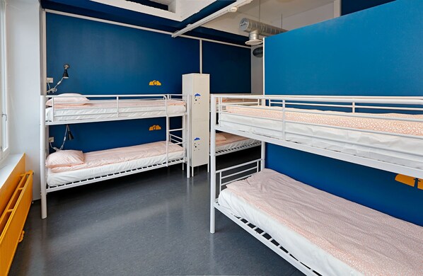 A bunk room with three bunk beds, a desk, and a radiator.