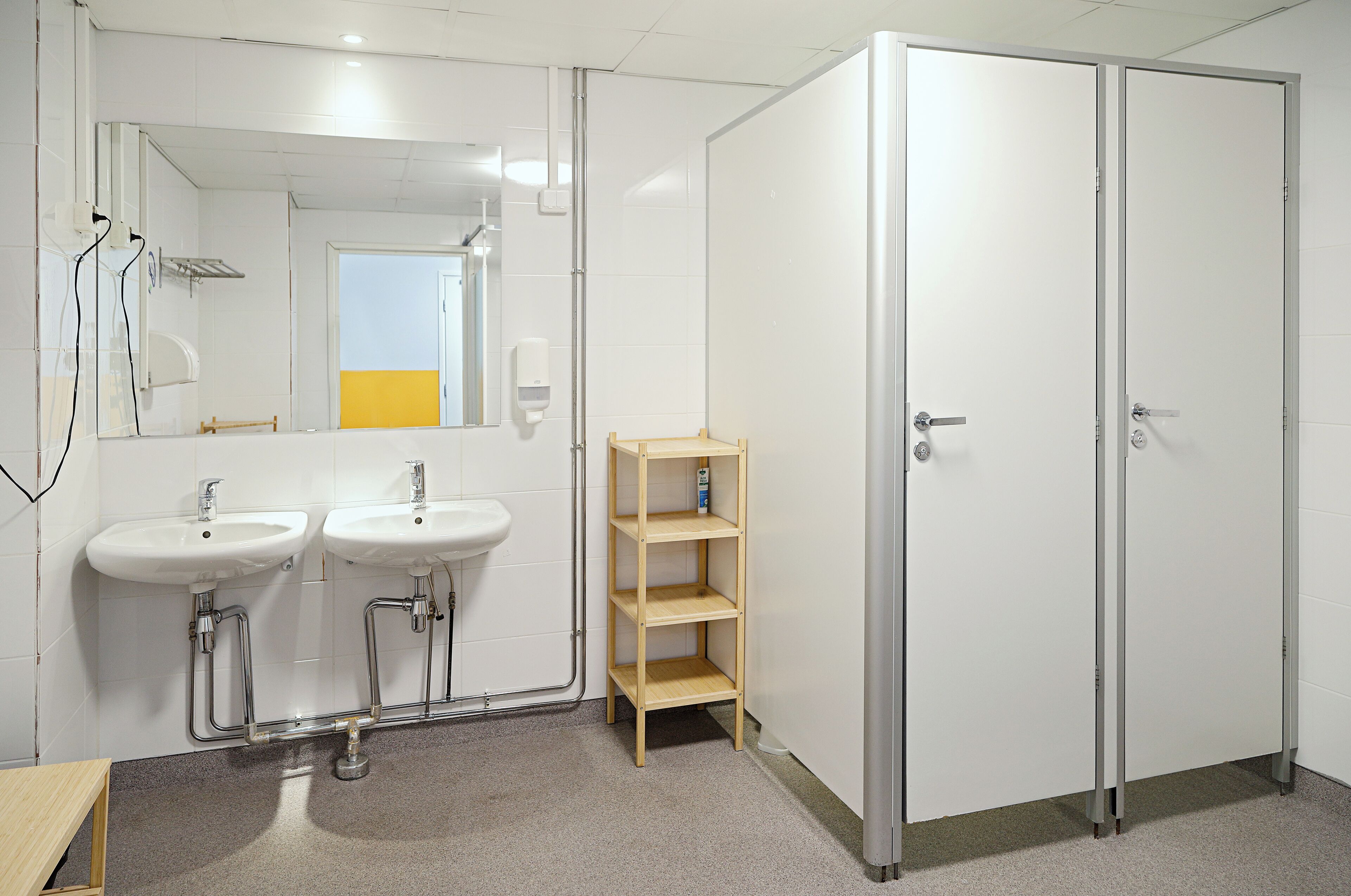 A bathroom with two sinks, a mirror, and a wooden shelf.