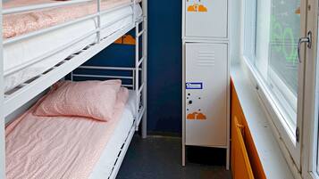 A bunk bed room with a window, a radiator, and a cabinet with a thermostat.
