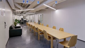 Una sala de conferencias con una larga mesa, sillas, un sofá y una planta en maceta.