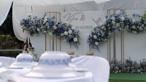 A wedding reception setup with white and blue floral arrangements, a white tent, and a table with a white tablecloth. - Khun Mai Baan Suan Resort (Mae Ai)