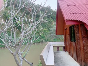 A wooden building with a red roof overlooking a river. - Khun Mai Baan Suan Resort (Mae Ai)