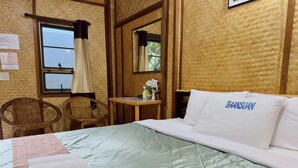 A hotel room with a bed, two wicker chairs, a small table, and a window with curtains. - Khun Mai Baan Suan Resort (Mae Ai)