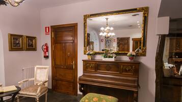 Una habitación con puerta de madera, un banco, un espejo, una araña y un radiador.
