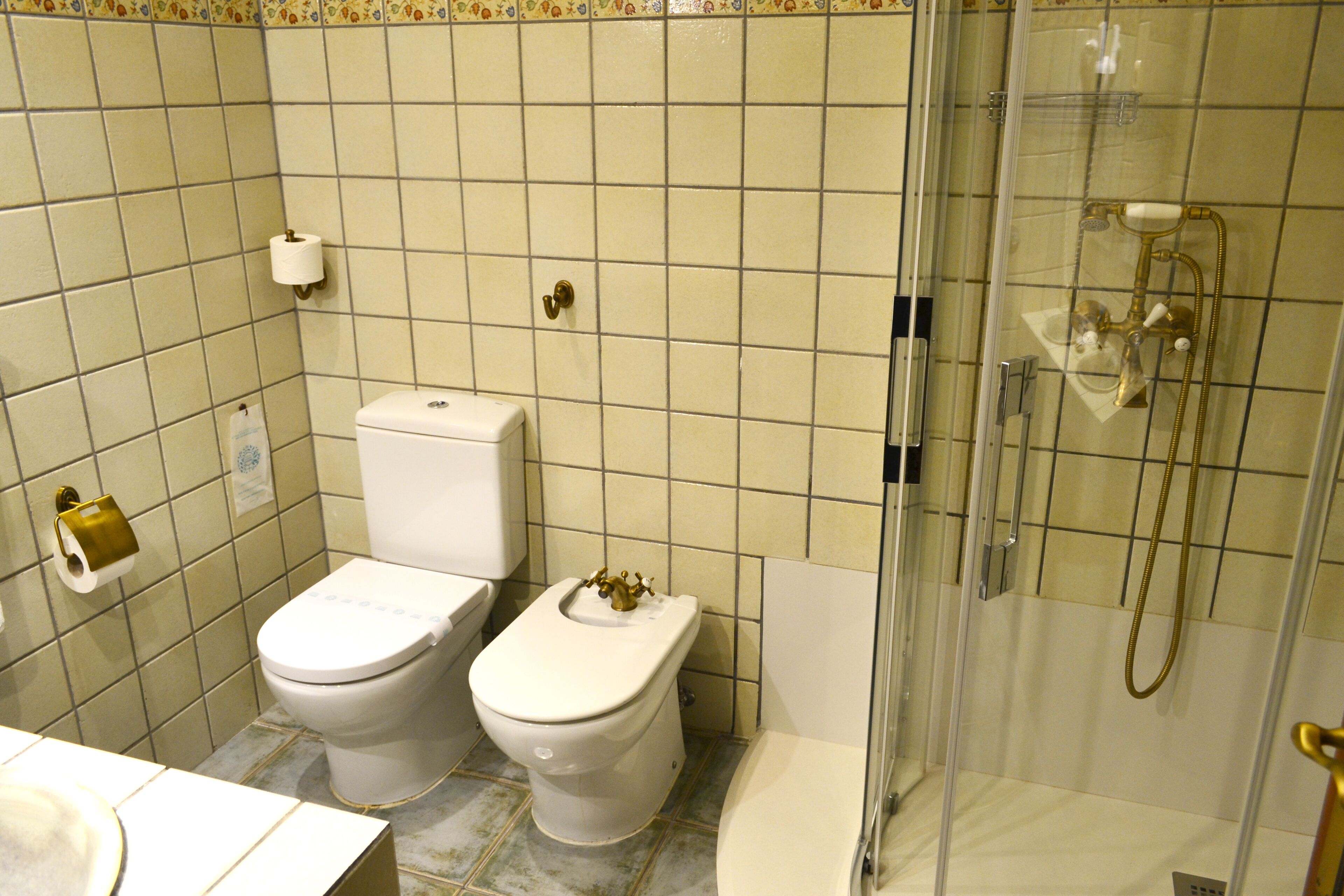 Un baño con dos inodoros, una ducha y un lavabo.