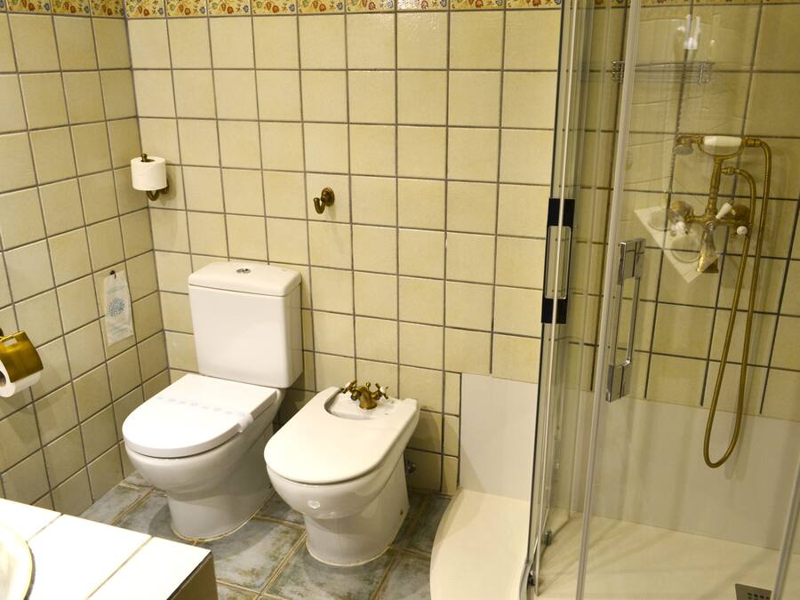Un baño con dos inodoros, una ducha y un lavabo.