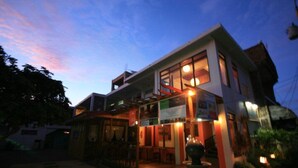 A two-story building with a restaurant on the ground floor, featuring a covered outdoor seating area and a well-lit entrance. - Antonio's Pension House (Dipolog)