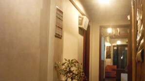 A hallway with a tiled floor, a potted plant, and a wooden bench. - Antonio's Pension House (Dipolog)
