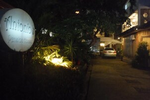 Vista nocturna de la entrada de un edificio con un cartel que dice 'Antonio's Pensionhouse'.