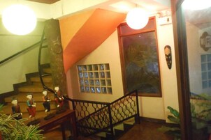 Una escalera con barandilla negra, una pared con ventana y una puerta con símbolo de Wi-Fi.