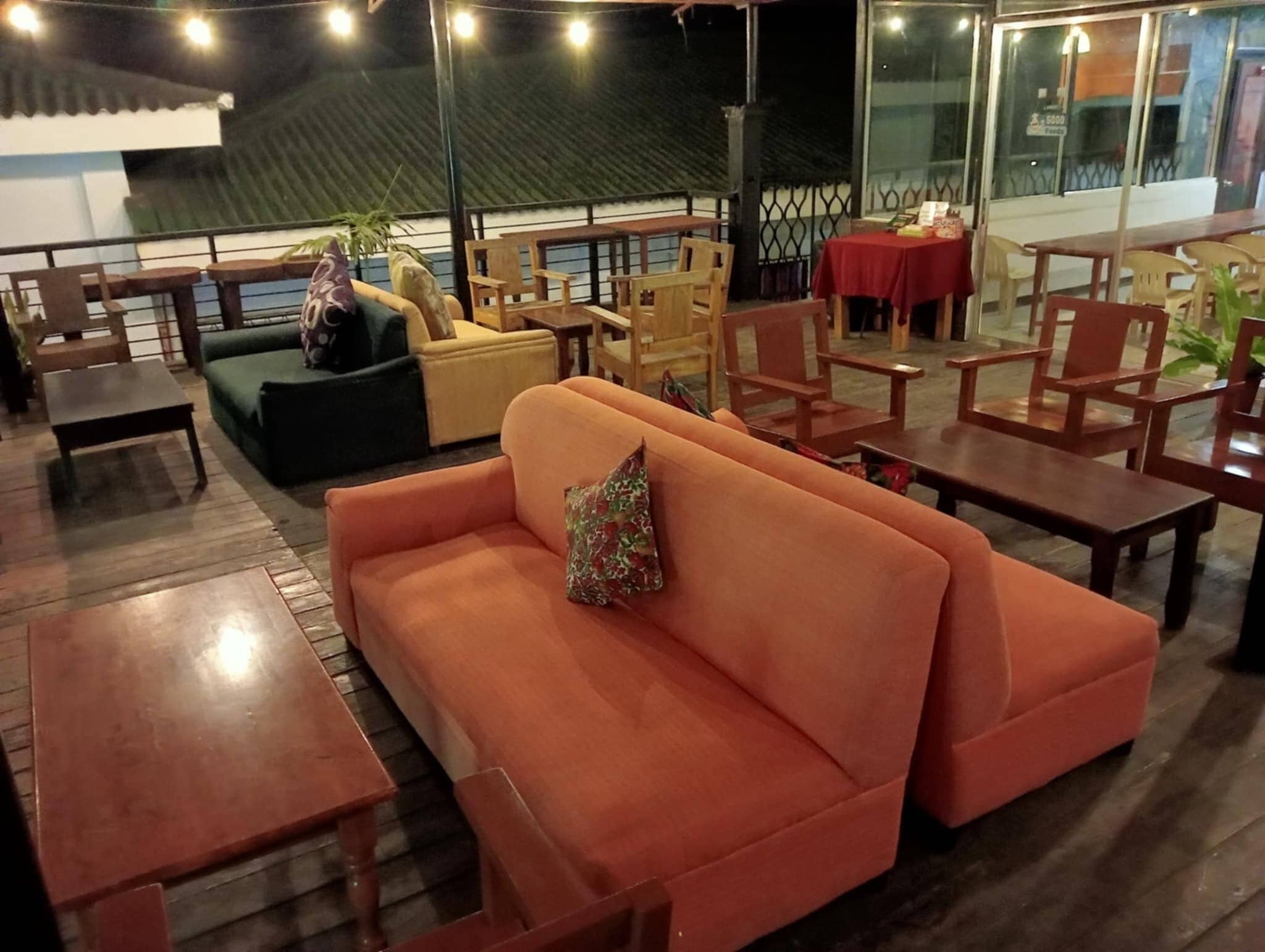 A restaurant with outdoor seating including a sofa and tables.