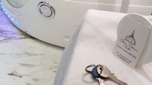 A white spa tub with a control panel, a key, and a business card on a marble surface. - Chain Vatican Suites (Rome)