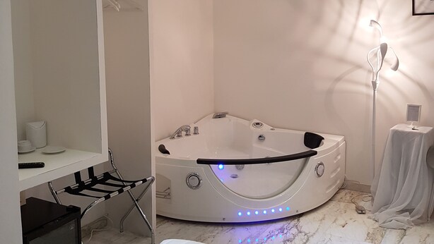 A modern bathroom with a freestanding bathtub, a vanity with a mirror, and a towel rack. - Chain Vatican Suites (Rome)