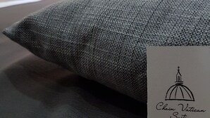 A grey textured pillow with a business card on it. The card reads "Chain Vatican Suites" and provides a telephone number and email address. - Chain Vatican Suites (Rome)