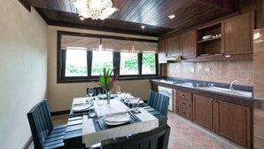 Cozinha moderna com armários de madeira, sala de jantar com mesa posta para quatro pessoas e uma janela grande que proporciona luz natural.