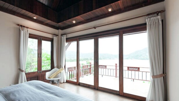 Quarto com uma cama grande, uma cadeira e varanda com vista para as montanhas.