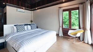 Quarto com uma cama grande, uma poltrona de balanço, uma janela com cortinas e um ventilador de teto.